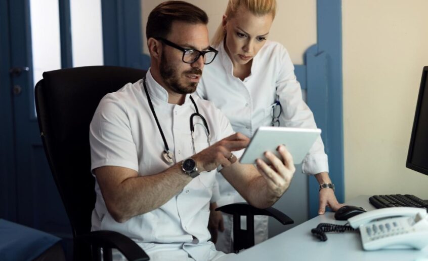 a male doctor and nurse cooperating while examining electronic medical records