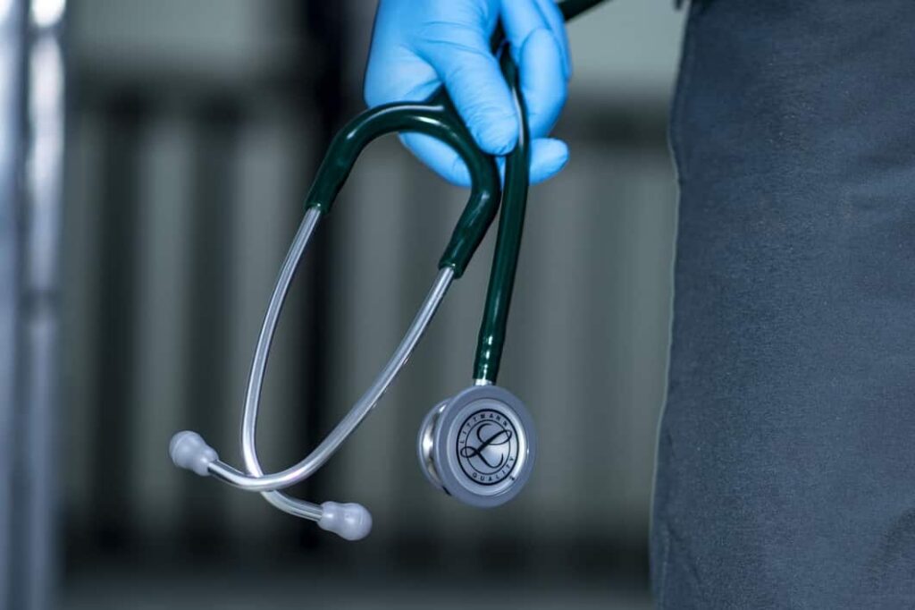 Close-up of a hand in a blue glove holding a stethoscope