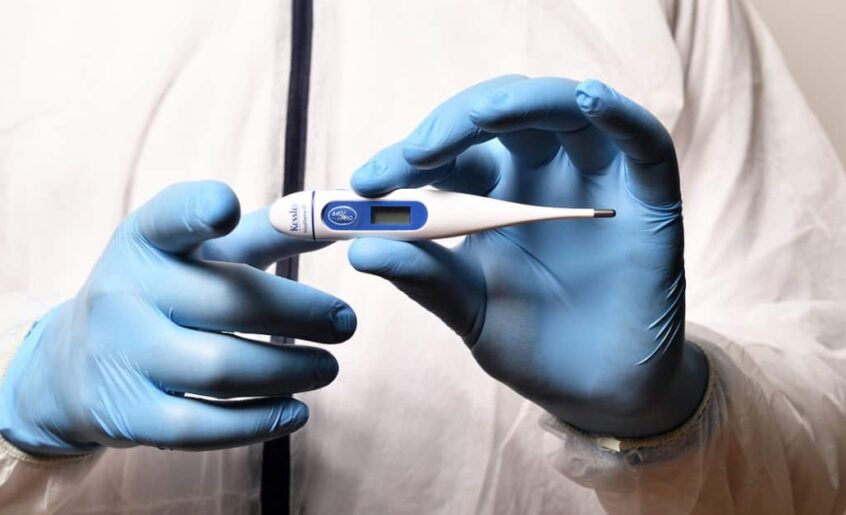 Gloved hands holding a digital thermometer