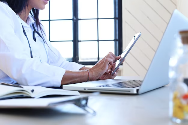 Doctor using a phone in front of a laptop