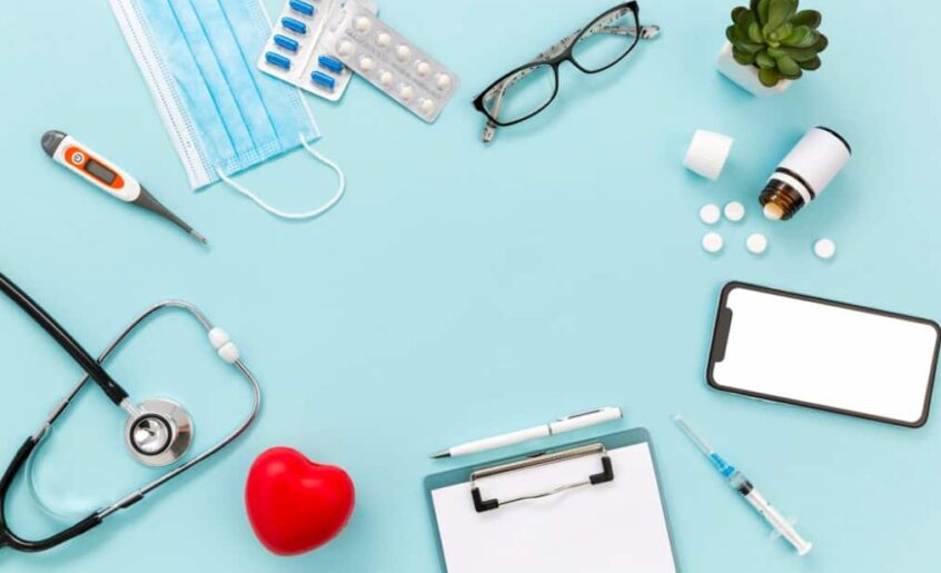 Healthcare items including a mask, thermometer, and smartphone on a blue background